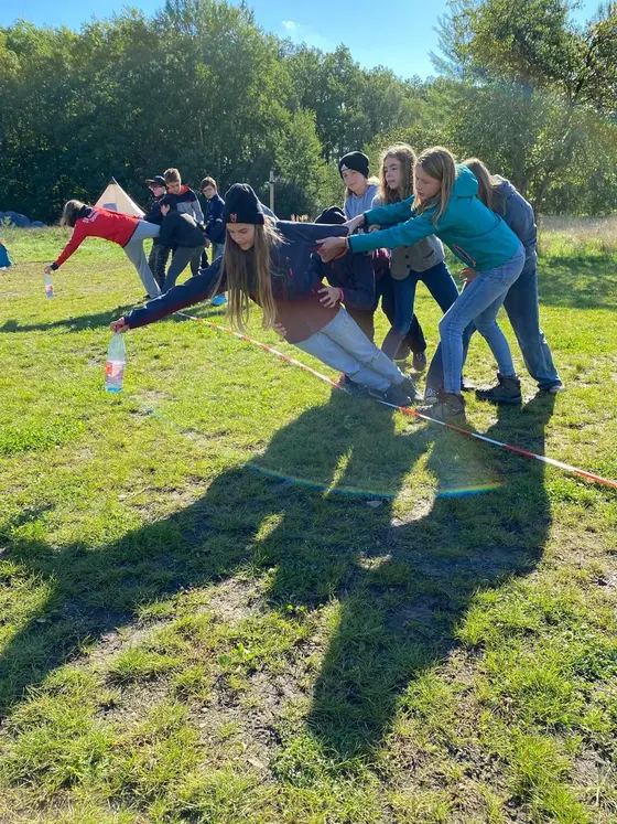 Gruppe Jugendlicher hilft sich gegenseitig beim Balancieren auf der Slackline